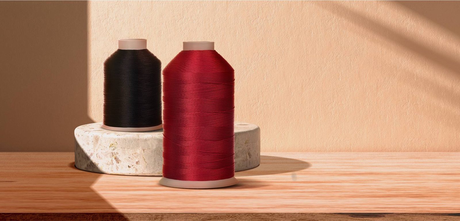 Cones de linha de costura em tons de vermelho sobre bancada clara.
